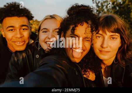 Des amis joyeux prennent le selfie à l'extérieur pendant le coucher du soleil Banque D'Images