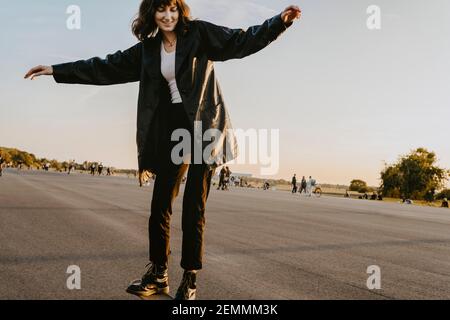 Jeune femme patinant sur la route dans le parc pendant le coucher du soleil Banque D'Images