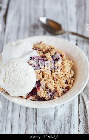 Mûre et bleuet Cobbler recouvert d'un gruau doré croustillant à la crème glacée. Mise au point extrême sélective avec arrière-plan flou. Banque D'Images