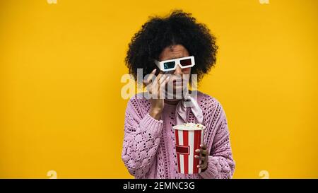 Bouleverser la femme afro-américaine en lunettes 3d pleurant et tenant pop-corn isolé sur jaune Banque D'Images