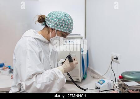 Mains d'un technicien dentaire avec masque chirurgical et lunettes de polissage des prothèses dentaires sur sa table. Concept de santé Banque D'Images