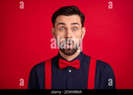 Portrait de jeune beau surpris gentleman surpris d'entendre la rumeur de potins mauvaise nouvelle isolée sur fond rouge Banque D'Images