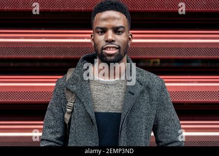 Portrait d'un homme d'affaires afro dans la ville sur un fond rouge Banque D'Images