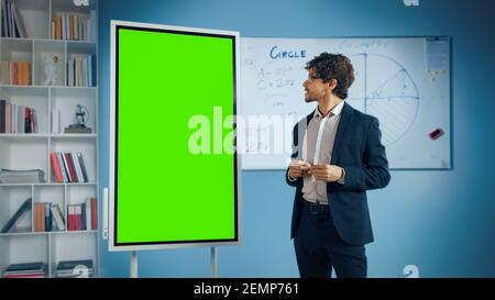 Portrait d'un professeur amical explique la leçon à une salle de classe, utilise le tableau blanc numérique à écran vert. Un homme d'affaires prospère parle de croissance de projet Banque D'Images