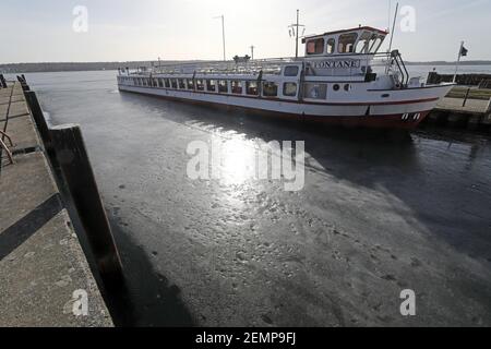 24 février 2021, Mecklembourg-Poméranie occidentale, Waren (Müritz): Le soleil se reflète dans la glace sombre du Müritz devant un navire à passagers. Malgré les températures douces pendant plus d'une semaine, une glace fermée arrête toujours toute navigation sur le Müritz, le plus grand lac intérieur d'Allemagne avec une superficie de 117 kilomètres carrés. Photo: Bernd Wüstneck/dpa-Zentralbild/ZB Banque D'Images