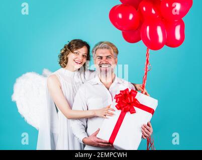 Couple en Saint-Valentin avec ballons de coeur et cadeau. Anges familiaux. Cadeaux de la Saint-Valentin. Banque D'Images
