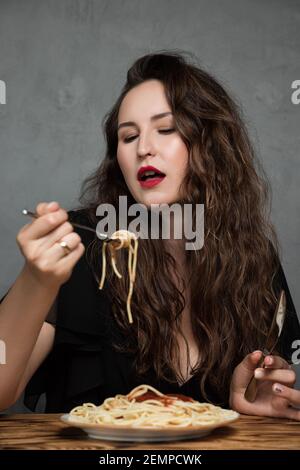 Une belle jeune femme mange des pâtes spaghetti italiennes Banque D'Images