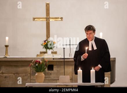 Erfurt, Allemagne. 25 février 2021. Pendant le service commémoratif, le pasteur Bernd Prigge allume six bougies pour les 247 victimes d'un RAID à l'explosif sur le monastère d'Augustinien le 25 février 1945. Deux nouvelles croix d'ongle sont également présentées au service commémoratif, après que l'ancien a été volé en juillet dernier dans des circonstances encore inexpliquées. Credit: Michael Reichel/dpa-Zentralbild/dpa/Alay Live News Banque D'Images