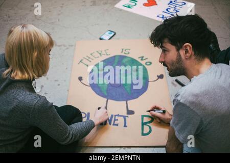 Un jeune manifestant, homme et femme, prépare une affiche pour les questions environnementales Banque D'Images