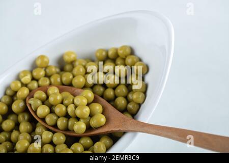 Photo en gros plan de l'olive verte marinée dans un bol blanc avec cuillère en bois Banque D'Images