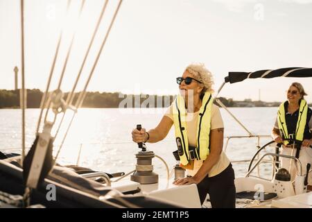 Femme sénior naviguant avec une amie en bateau sous le soleil jour Banque D'Images