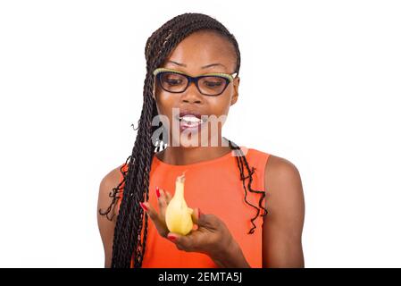 jeune fille debout dans des verres sur fond blanc regardant une banane, surprise. Banque D'Images