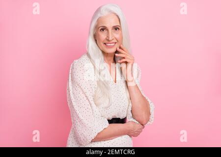 Portrait d'une femme aux cheveux gris et à l'esprit enjoué et attrayante qui touche le visage posant isolé sur fond rose pastel Banque D'Images