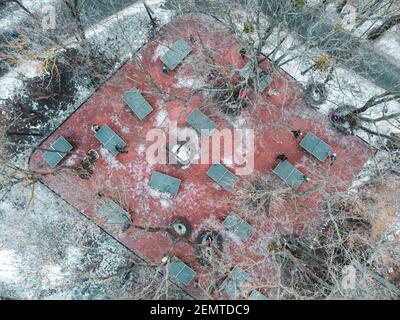 Vue aérienne sur les arbres enneigés. Tennis de table, aire de jeux rouge en hiver, sans personne. Terrain de jeux de ping-pong dans le jardin botanique sa Banque D'Images