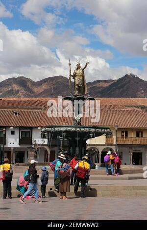 Une fontaine avec une statue du roi Inca Pachacutec sur la place principale de Cusco, au Pérou, avec des locaux rassemblés devant Banque D'Images