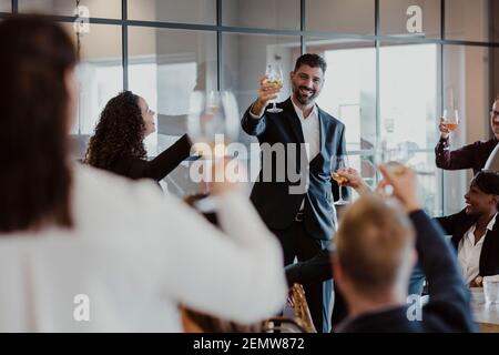 Des hommes et des femmes qui toastent des lunettes de vin pendant la fête de bureau Banque D'Images