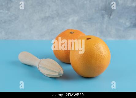 Deux oranges et un alésoir en bois sur fond bleu Banque D'Images