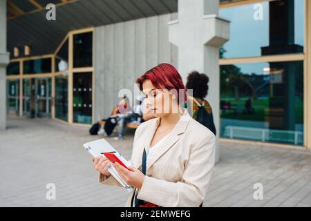 REDHEAD étudiante à l'aide d'un smartphone sur le campus universitaire Banque D'Images