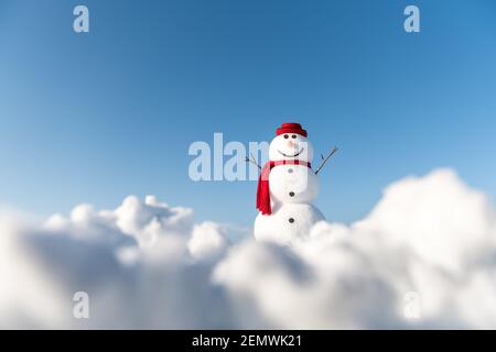 Bonhomme de neige amusant dans un élégant chapeau rouge et un scalf rouge sur un terrain enneigé. Ciel bleu sur fond Banque D'Images