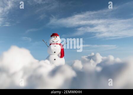 Bonhomme de neige amusant dans un élégant chapeau rouge et un scalf rouge sur un terrain enneigé. Ciel bleu sur fond Banque D'Images