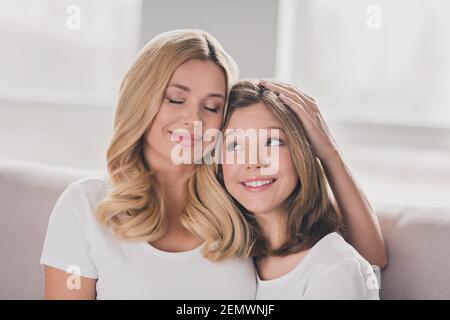 Photo de charmante adorable maman fille porter t-shirts blancs souriant un canapé près de la maison Banque D'Images