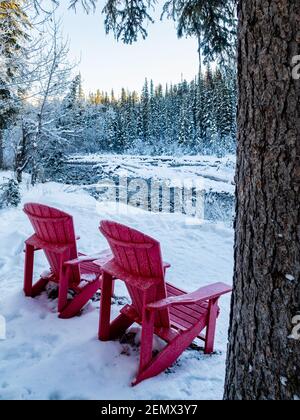 Deux chaises Adirondack rouges à proximité de la rivière Maligne en hiver Banque D'Images