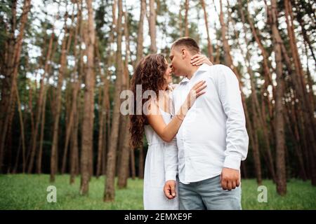 Un couple en amour beau jeune homme et femme sont embrassant et embrassant dans un parc d'été par une journée ensoleillée. La date dehors, bien habillée, si excitée et lov Banque D'Images