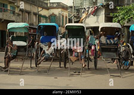 Les tireurs de pousse-pousse prennent une pause dans une rue près du temple Kalighat Kali à Kolkata, Bengale occidental, Inde. Banque D'Images