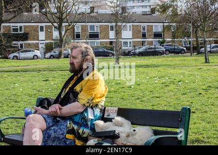 Londres, Royaume-Uni. 23 février 2021. Un militant s'assoit sur un banc et marche autour de jouer de la musique forte afin d'ennuyer les huissiers et les voisins. C’est le deuxième jour de « séance d’arbres » aux York Gardens de Londres, à Battersea. Pour sauver un peuplier noir de 100 ans, trois activistes l'ont grimpé et occupé pendant la nuit du 21 au 22 février. L'arbre devait être coupé pour faire place à un nouveau câble électrique, qui faisait partie du programme de régénération du logement local. Banque D'Images