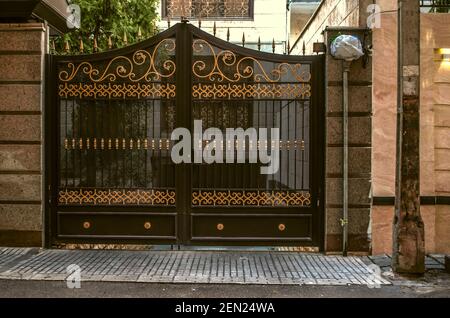 Porte double traditionnelle en fer forgé portes noires avec décoration Grating et mis en évidence avec des motifs jaunes d'or le long de la rue épidoine À Teh Banque D'Images