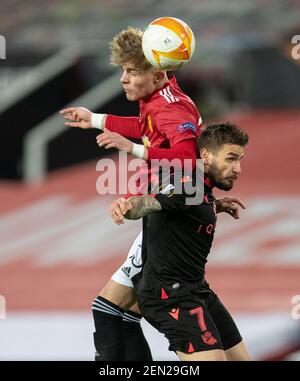 Manchester, Royaume-Uni. 26 février 2021. Brandon Williams (L) de Manchester United pose des défis pour une tête avec le Portu Cristian de Real Sociedad lors de l'UEFA Europa League Round of 32 second Leg football match entre Manchester United et Real Sociedad à Manchester, en Grande-Bretagne, le 25 février 2021. Credit: Xinhua/Alay Live News Banque D'Images