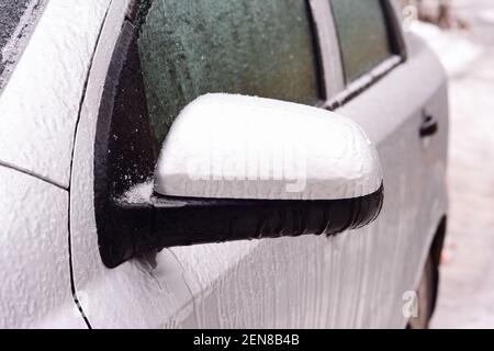 Une voiture gelée recouverte de glace. Comment dégivrer la voiture gelée, ouvrir une porte de voiture fermée gelée et éviter d'endommager la peinture de la voiture par la glace. Banque D'Images