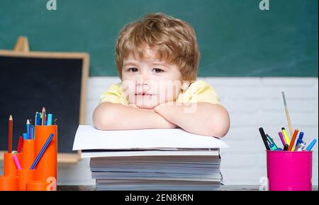 Élève à l'école en classe. Joli petit enfant d'âge préscolaire près du tableau noir. Éducation des enfants. Retour à l'école. Mignon enfant industriel est assis à un bureau avec Banque D'Images