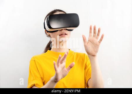 Un portrait d'une jeune jolie femme portant des lunettes de réalité virtuelle, tenant ses mains, essayant de toucher quelque chose. Arrière-plan blanc. Le concept de Banque D'Images