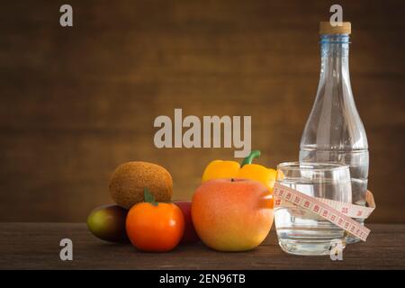 eau et mètre ruban avec fruits sur parquet. Concept de santé et de forme physique Banque D'Images