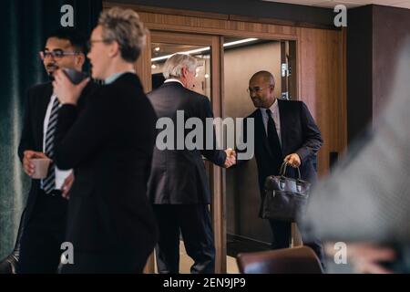 Accueil souriant des hommes d'affaires par des collègues dans la salle de conseil Banque D'Images