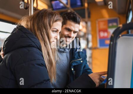 Femme achetant un billet debout par un homme en train de se déplacer dans le tram Banque D'Images