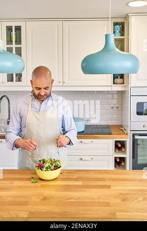 Homme cuisant à la maison préparant de la salade dans la cuisine. Photo de haute qualité Banque D'Images