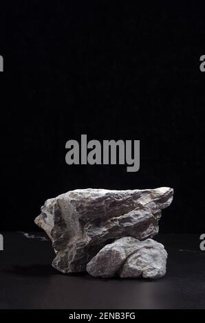 Podium en pierre de marbre gris pour l'emballage et la présentation cosmétique sur fond noir, vertical. Style naturel et résistant. Banque D'Images