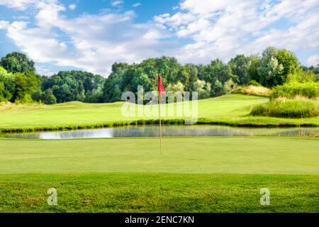 Mettre le vert avec un drapeau sur un parcours de golf un jour d'été Banque D'Images