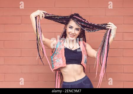 Jeune fille moderne avec des dreadlocks colorés sur fond de mur Banque D'Images