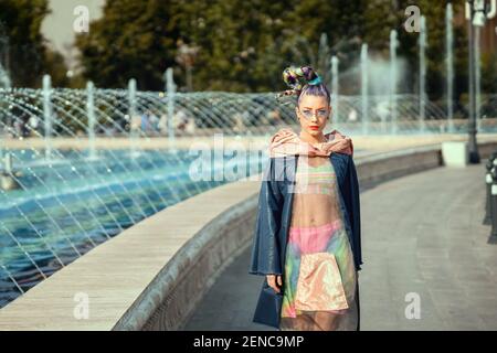 Jeune fille moderne avec des dreadlocks colorés et des vêtements de mode de rue marche dans la rue de la ville Banque D'Images