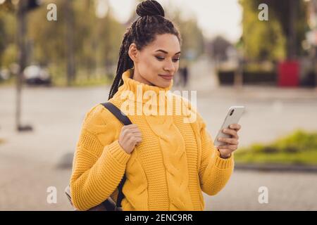 Photo de jeune charmant joli charmant heureux positif peau sombre femme utilisant un smartphone à l'extérieur Banque D'Images