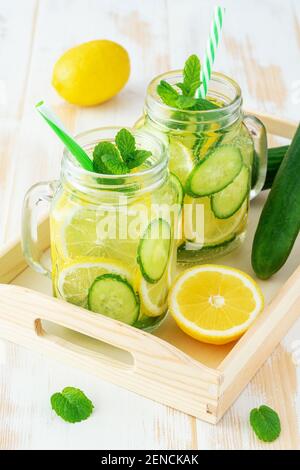De l'eau de détox avec des tranches de citron et de concombre dans un pot sur une table en bois. Concept sain. Banque D'Images