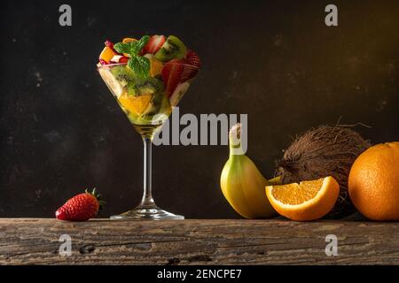Cocktail de fruits en verre martini sur table en bois. Concept végétalien alimentaire. Banque D'Images