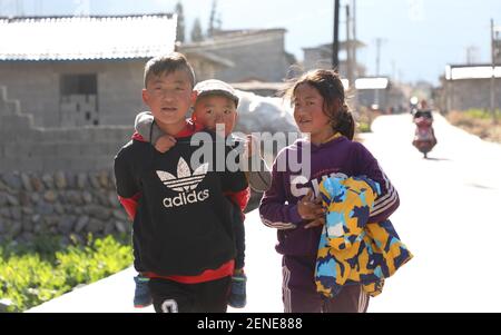 (210226) -- LIANGSHAN, 26 février 2021 (Xinhua) -- Jijue Jizhu (1er L) marche sur une route avec son frère et sa sœur cadet dans la province du Sichuan, dans le sud-ouest de la Chine, le 24 février 2021. Par une journée enneigée en février 2018, un jeune garçon de neuf ans portant son frère cadet à l'arrière descendait dans la préfecture autonome de Liangshan Yi, dans la province du Sichuan, sur le chemin de la maison de son grand-père maternel sur un site de réinstallation. Le correspondant de Xinhua a capturé l'instant. La photo a déplacé beaucoup de Chinois. Avec l'aide de la lutte contre la pauvreté ciblée, la famille de Jijue Jizhu fait ses adieux à la maison adobe dans un Banque D'Images