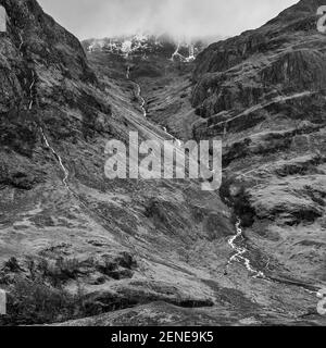 Image spectaculaire et spectaculaire du paysage noir et blanc de Three Sisters À Glencoe, dans les Highlands écossais, par une journée d'hiver humide Banque D'Images