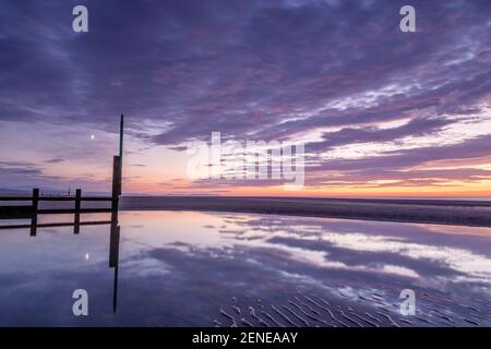 Coucher de soleil sur la plage de Rhyl à marée basse au nord Côte du pays de Galles Banque D'Images
