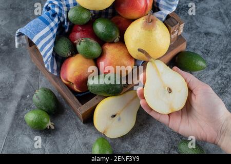 Vue de dessus du panier de fruits frais. Femelle tenant demi-poire coupée Banque D'Images