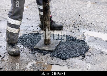 ouvrier poussant l'asphalte de bitume dans le trou. réparation et entretien des routes Banque D'Images